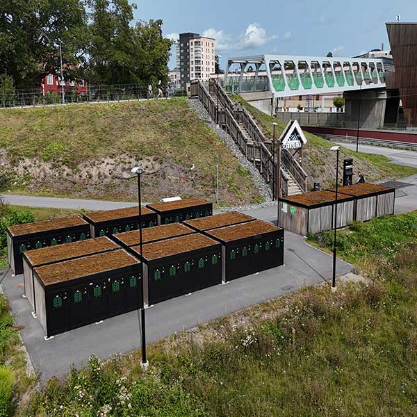 Översikt av FalcoLok Q cykelboxar vid Kallhäll station i Järfälla, modulär cykelparkering med gröna sedumtak nära tågstationen.